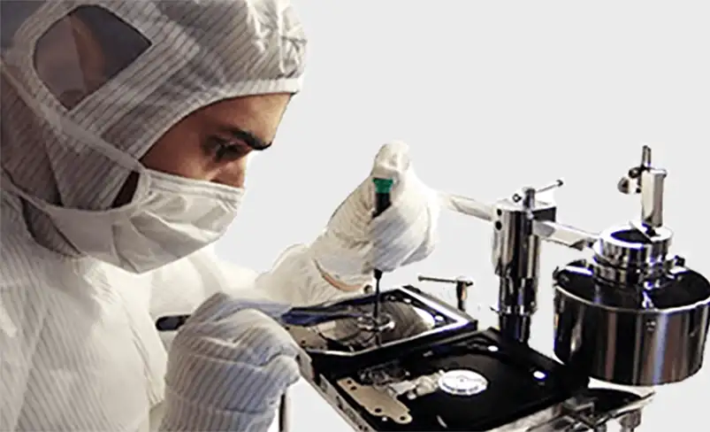 Technician repairing a hard drive in a clean room environment.